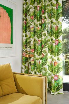 a living room filled with furniture and a window covered in green curtains next to a painting on the wall