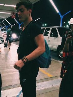 a group of young men standing next to each other in front of parked cars at an airport