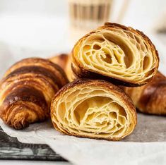 three croissants sitting on top of a piece of paper next to a cup