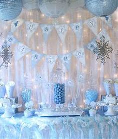 a table topped with lots of blue and white desserts next to a wall covered in snowflakes