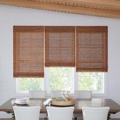 a dining room table with four chairs and bamboo blinds