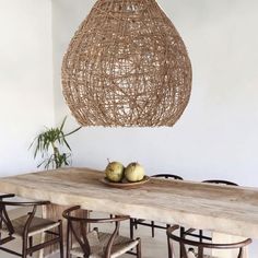 a wooden table topped with two green apples under a large light hanging from the ceiling