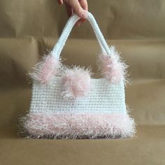 a hand holding a pink and white purse