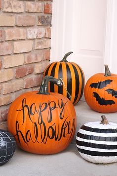 three pumpkins with happy halloween written on them are sitting in front of a door