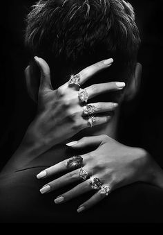 a man and woman with their hands on each other's shoulders, both wearing diamond rings