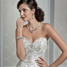 a woman in a wedding dress posing for the camera with her hand on her cheek