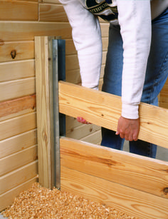 a person holding onto the side of a wooden structure with wood shavings on it