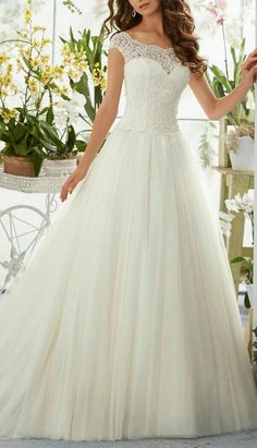 a woman in a white wedding dress standing next to a flower pot and wearing a tiara