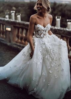 a woman in a white wedding dress standing on a bridge with candles around her head