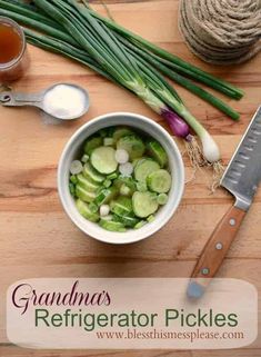 a bowl filled with sliced cucumbers next to a knife and some green onions