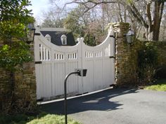 a white gate with brick pillars and an iron lamp post in front of the house