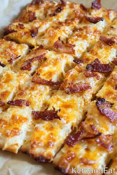 a pizza with cheese and bacon on it is cut into squares to be served for consumption