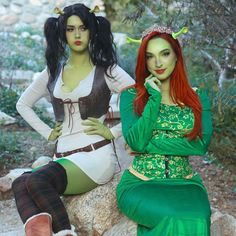 two women dressed in costumes sitting on rocks