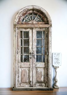 an old wooden door sitting on top of a hard wood floor next to a sign