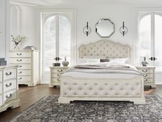 a bedroom with white furniture and large windows