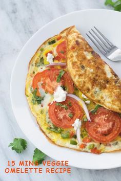 an omelet with tomatoes and onions on a white plate next to a fork