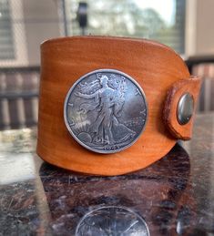 "Leather Boho Cuff with Lady Liberty Concho Sable brown-stained leather  Signature asymmetrical cufff All stains will be slightly different but similar to the colors displayed.  Each piece is unique in exact color pattern.  Perfect to stack with my other bracelets.  Fits a 7\" wrist perfectly Link to Tenile Creations LLC storefront: www.etsy.com/shop/TenileCreations  HOW TO MEASURE YOUR WRIST For at home wrist measurements: Measure your wrist circumference just above the bone. Feel your wrist to locate the knobby bones on either side of your arm and place your string on the side just above it. Wrap the string around your wrist until it's snug and mark where it overlaps the end. Straighten out the string and hold it against a ruler to find your measurement. Write the measurement down so you Handmade Brown Cuff Bracelet, Classic Brown Cuff Bracelet, Classic Brown Leather Strap Cuff Bracelet, Hand Tooled Brown Cuff Bracelet, Brown Leather Strap Cuff Bracelet, Unique Brown Cuff Bracelet, Brown Waxed Finish Cuff Bracelet, Vintage Brown Hand Tooled Cuff Bracelet, Vintage Brown Hand-tooled Cuff Bracelet