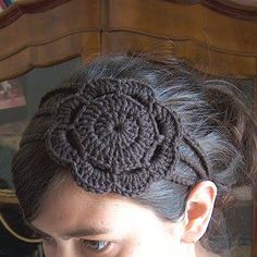 a woman wearing a crocheted headband with a flower on it's side