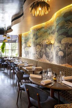 an empty restaurant with tables and chairs in front of a large painting on the wall