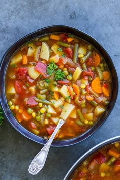 two bowls filled with vegetable soup on top of a table