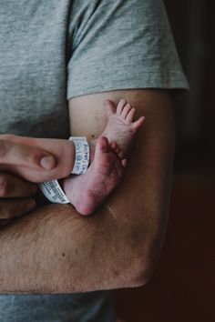 a man holding a baby in his arms while wearing a band around it's wrist