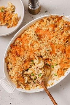 an oval casserole dish filled with macaroni, cheese and vegetables on a white table