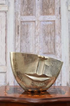 a gold bowl sitting on top of a wooden table next to a white and brown door