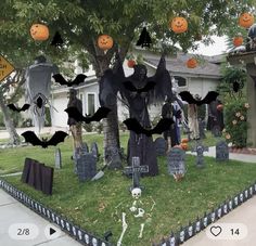 halloween decorations in front of a house with bats and pumpkins hanging from the trees