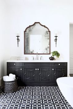 a bathroom with a black and white tile floor, mirror, sink and bathtub