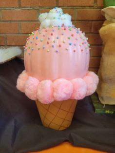 an ice cream cone decorated with sprinkles and pom - poms