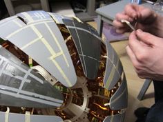 a person is working on a model of a building with metal strips around the edges