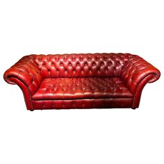 a red leather couch sitting on top of a white floor