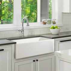 a white kitchen sink sitting under a window next to a dishwasher and cabinets