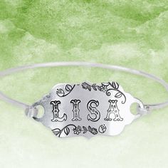 this is an image of a silver bracelet with the word us in black letters on it