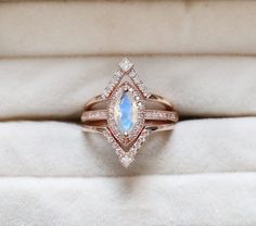 an engagement ring with a pear shaped blue stone surrounded by small diamonds in a box