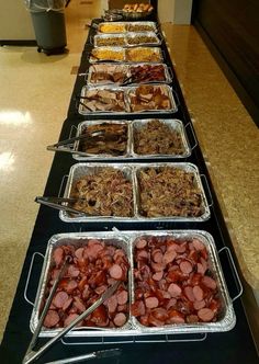 several trays of food are lined up on a long table