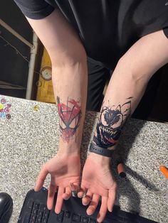 two people with tattoos on their arms are sitting in front of a keyboard and computer