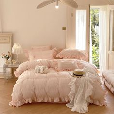 there is a bed with pink sheets and pillows