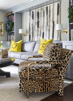 a living room with leopard print furniture and yellow pillows on the couches in front of a large painting