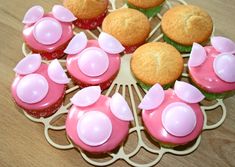 cupcakes with pink icing and flower decorations are arranged in a circle on a wooden table