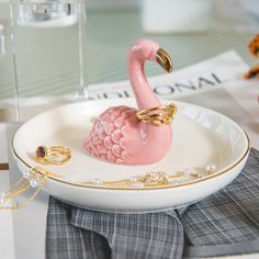 a pink flamingo figurine sitting on top of a white plate with gold chains