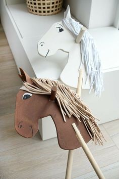 a wooden toy horse on top of a white table next to a basket and window