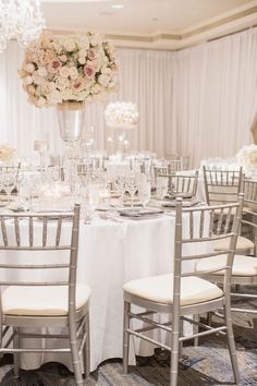 the tables are set up with white linens and silver chairs for an elegant wedding reception