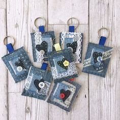 four pieces of denim with buttons and lace hanging from hooks on a white wooden surface