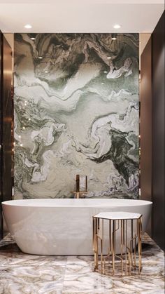 a bathtub in a bathroom with marble walls and flooring, along with two stools