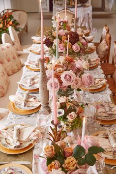 a long table is set with pink flowers and candles for an elegant dinner party or special occasion