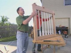 two men are working on an art piece in front of a house that is being built