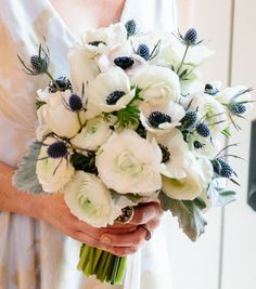 a woman holding a bouquet of white flowers in her hands and wearing a wedding dress