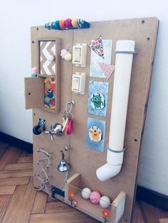 a bulletin board with magnets, pictures and other items attached to it on a wooden floor