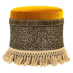 a leopard print ottoman with tassels and fringed trim on the bottom, against a white background